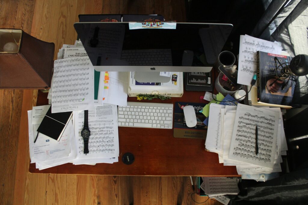 Overhead shot of an untidy desk with energy drinks, sticky notes, and reminders.