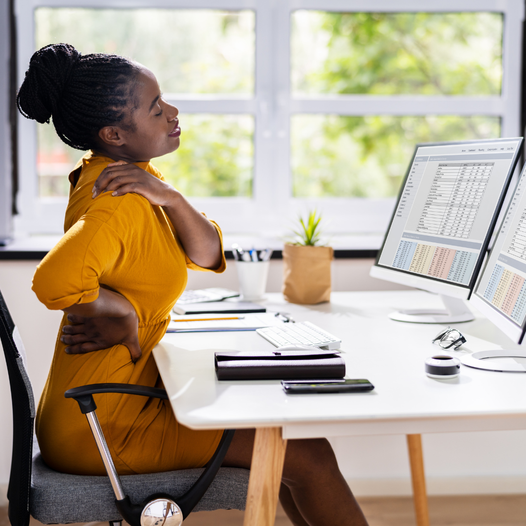 An office worker hunched over a laptop at a desk.